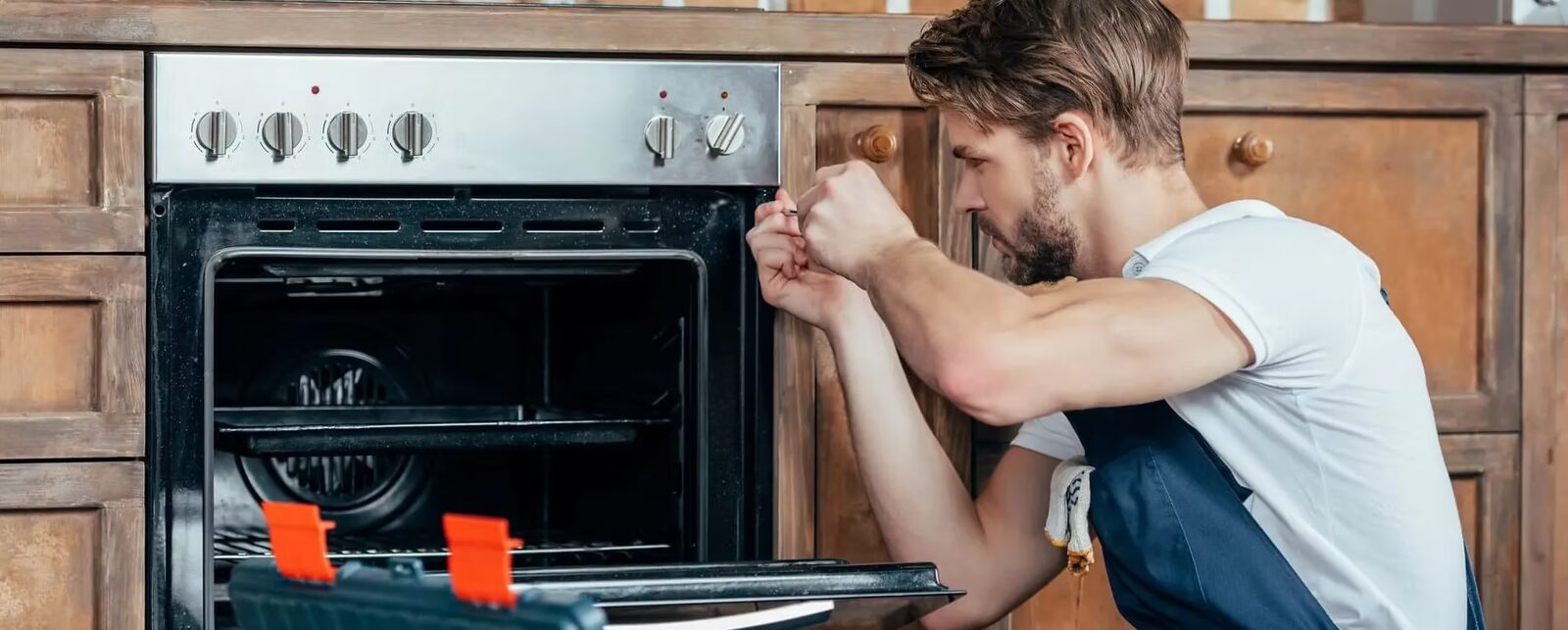 Técnico ajustando o forno de embutir a gás em uma cozinha residencial em Porto Alegre